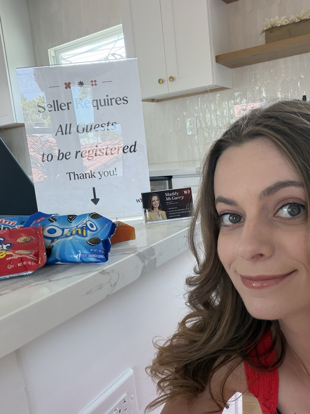 Maddy at an open house next to a guest sign-in sign and her business card